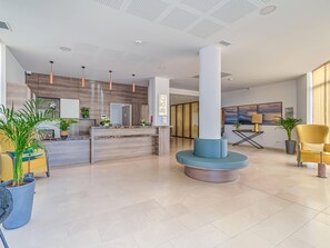 A modern hotel lobby with a reception desk, seating areas, and a large column. - Quality Aparthotel Marseille Centre Lodi (Marseille)