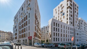 Un bâtiment moderne au design angulaire original, doté de nombreux balcons et d’une entrée imposante avec une enseigne.