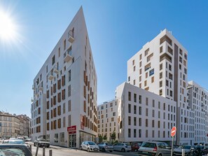 A modern building with a unique angular design, featuring multiple balconies and a prominent entrance with signage. - Quality Aparthotel Marseille Centre Lodi (Marseille)