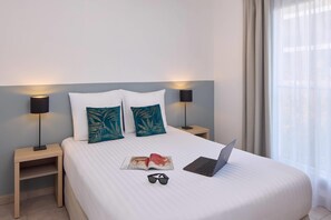 A neatly made bed with a laptop, sunglasses, and a magazine on a hotel room. - Quality Aparthotel Marseille Centre Lodi (Marseille)