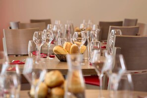 A dining table set with multiple wine glasses and a basket of bread. - Quality Aparthotel Chalon-sur-Saône Gare (Chalon-sur-Saone)