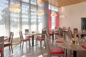 A modern dining area with round tables, red cushioned chairs, and pendant lighting. - Quality Aparthotel Chalon-sur-Saône Gare (Chalon-sur-Saone)