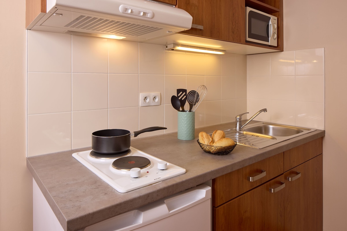 Una cocina con estufa, microondas, lavabo y armarios de madera.