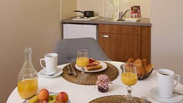 Una preparación para el desayuno que incluye una mesa, alimentos para el desayuno y una cocina con microondas y lavamanos.