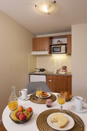Una preparación para el desayuno que incluye una mesa, alimentos para el desayuno y una cocina con microondas y lavamanos.