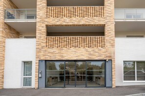 Ein modernes Gebäude mit Ziegelaußenwand, großem Glas Eingang und einem Balkon im oberen Geschoss.