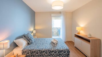 Une chambre à coucher avec un lit, des lampes de chevet, une table de chevet, une commode et une vue sur le balcon.