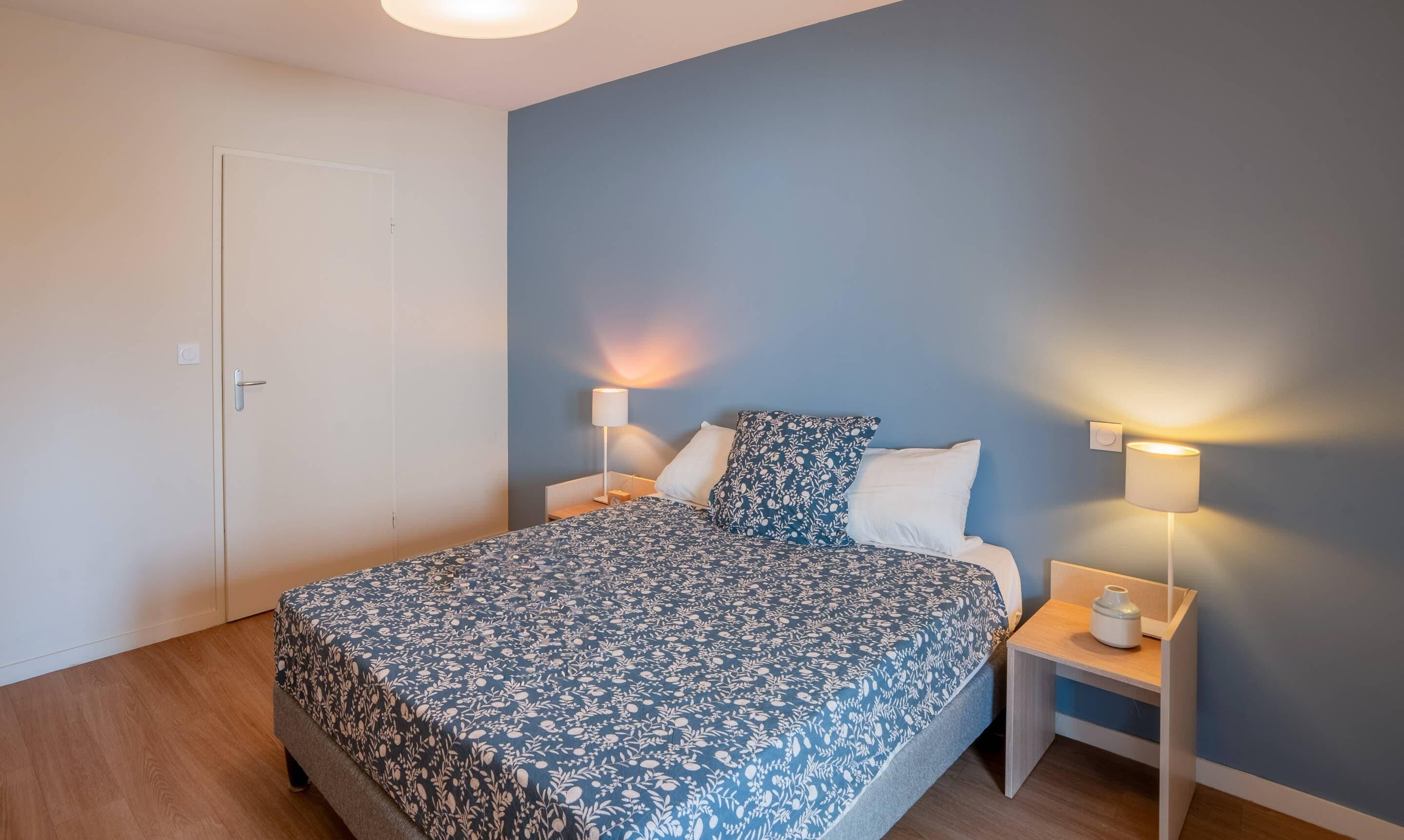 Ein Schlafzimmer mit einem Bett, zwei Nachttischen und einer Tür.