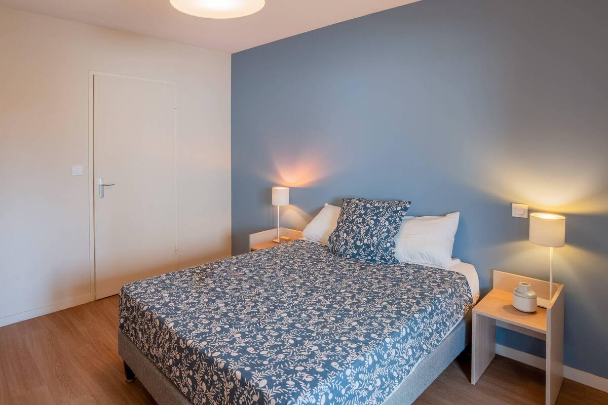 Ein Schlafzimmer mit einem Bett, zwei Nachttischen und einer Tür.