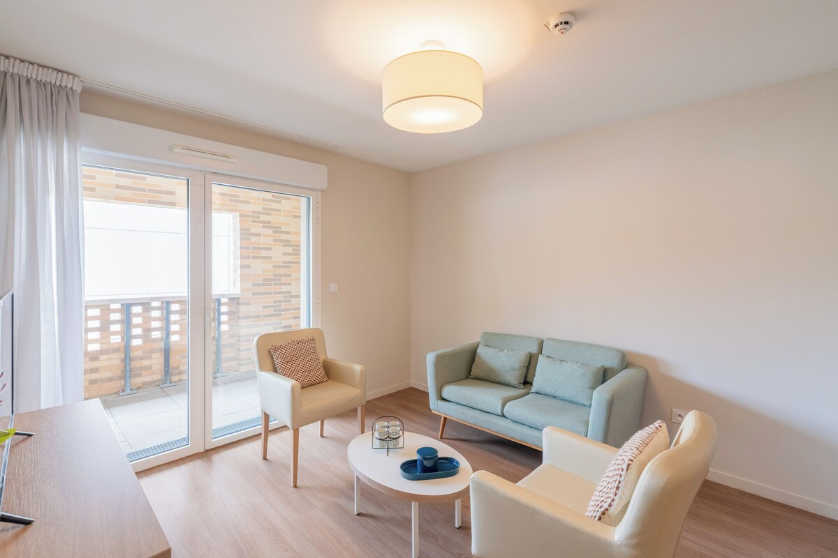 A modern living room with a sofa, chairs, a coffee table, and a sliding glass door to the outside.