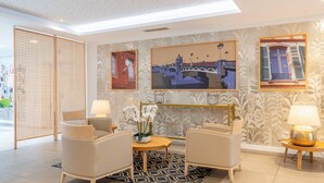 Eine moderne Hotelhalle mit Sitzgelegenheiten, dekorativer Wandkunst und Blick ins Freie.
