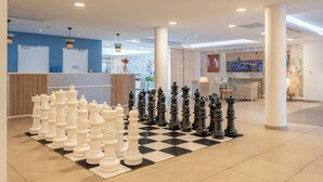 A lobby with a checkered floor chess set, a reception desk, and a large pillar. - Quality Aparthotel Toulouse Ponts Jumeaux (Toulouse)