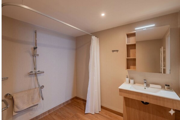 Ein modernes Badezimmer mit Dusche, Waschbecken und Spiegel.