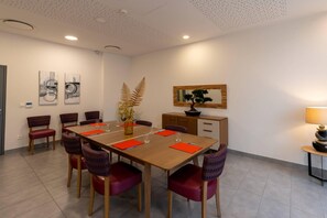 A dining area with a wooden table, red and purple chairs, and a potted plant. - Quality Aparthotel Mulhouse (Mulhouse)