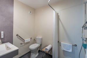 A bathroom with a toilet, a sink, a shower, and a towel rack. - Quality Aparthotel Mulhouse (Mulhouse)