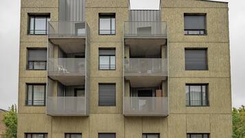 Een meerlaags gebouw met balkons, grote ramen en een bakstenen gevel.