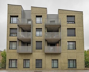 A multi-story building with balconies, large windows, and a brick facade. - Quality Aparthotel Mulhouse (Mulhouse)