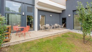 Un edificio moderno con un patio que cuenta con asientos al aire libre y un pequeño jardín.