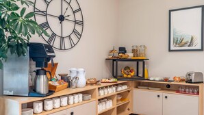 A breakfast bar with a coffee machine, a clock, and various food items. - Quality Aparthotel Villefontaine (Villefontaine)