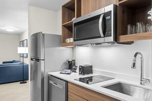 Een moderne keuken met een roestvrijstalen koelkast, een inbouwmagnetron, een koffiezetapparaat, een broodrooster en een spoelbak.
