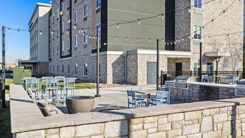An outdoor patio area with stone walls, blue chairs, and a barbecue station.