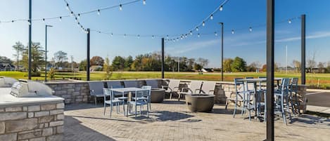 Un espace extérieur aménagé en terrasse, avec des sièges et des tables en pierre, ainsi que des guirlandes lumineuses.