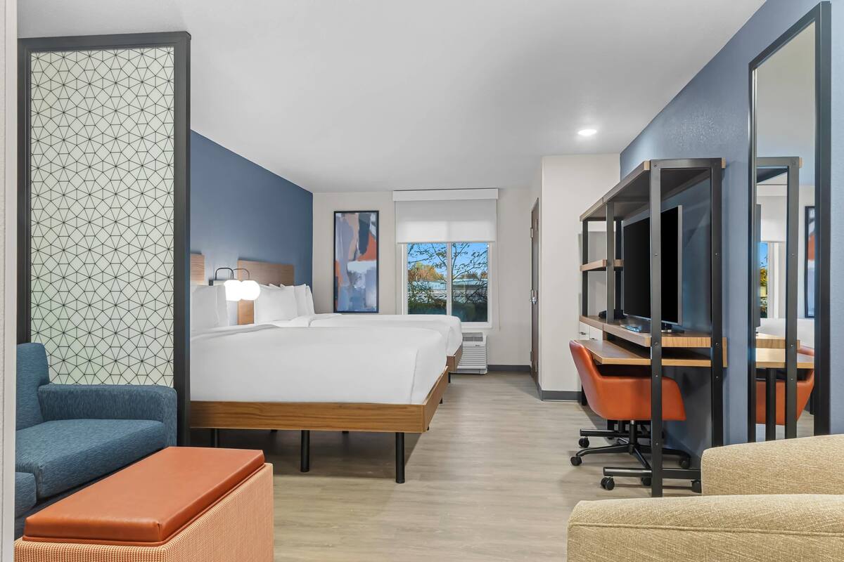 Ein Hotelzimmer mit einem großen Bett, einem Schreibtisch mit Computer, einem Sessel und einer Couch.
