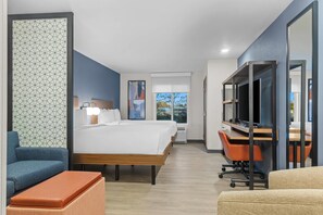 Una habitación de hotel con una cama grande, un escritorio con computadora, una silla y un sofá.