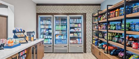 A clean, well-lit snack bar with refrigerated drinks, a variety of snacks, and a coffee machine.