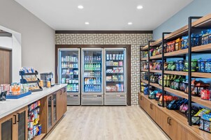Un bar de aperitivos limpio y bien iluminado, con bebidas refrigeradas, una variedad de bocadillos y una máquina de café.