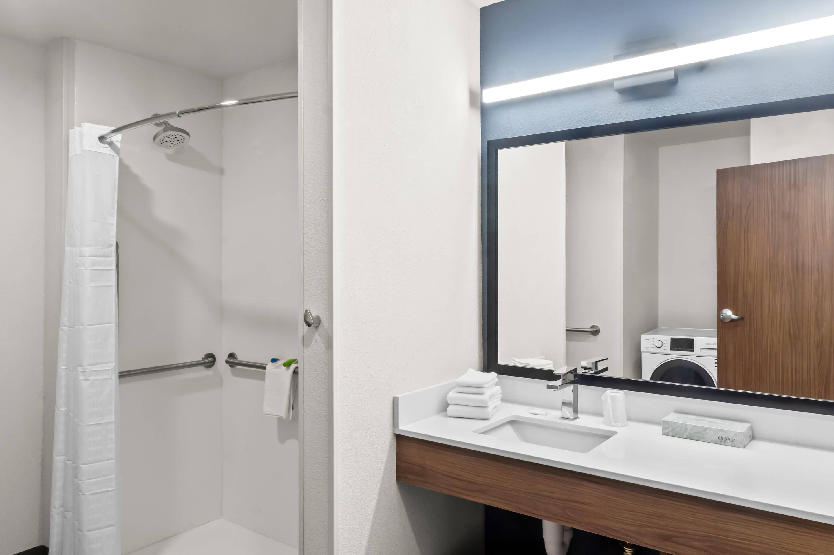 A modern bathroom with a shower, a sink, and a large mirror.
