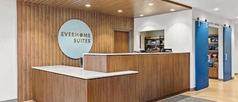 A reception desk with a wooden finish and a circular sign that reads "EVERHOME SUITES".