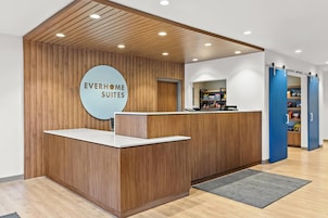 Un mostrador de recepción con acabado de madera y un letrero circular que dice "EVERHOME SUITES".