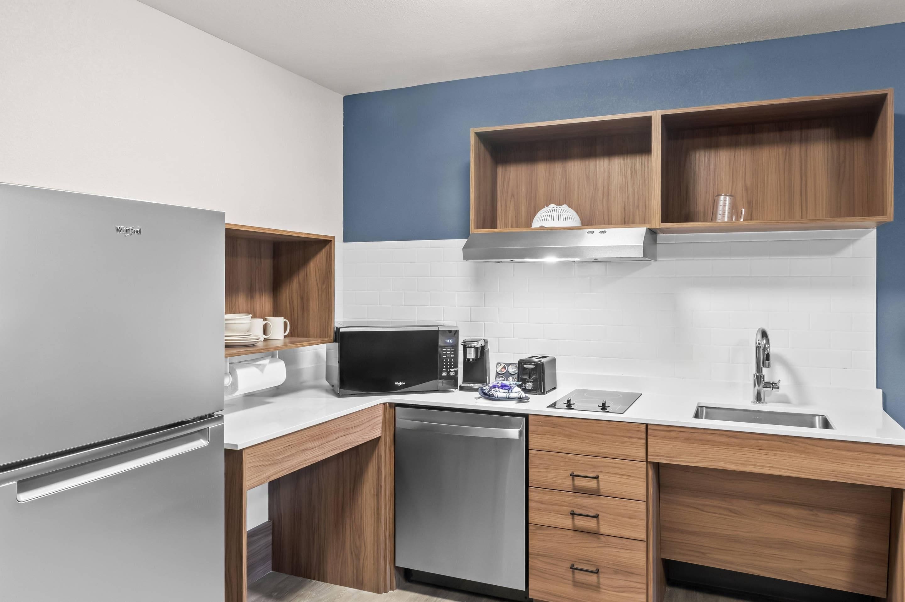 A modern kitchen with a stainless steel refrigerator, a microwave, a coffee maker, and a dishwasher.