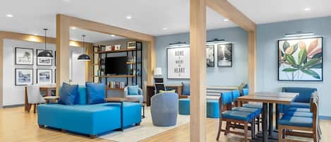 Een moderne woonkamer met een blauwe bank, een houten salontafel en een boekenkast.