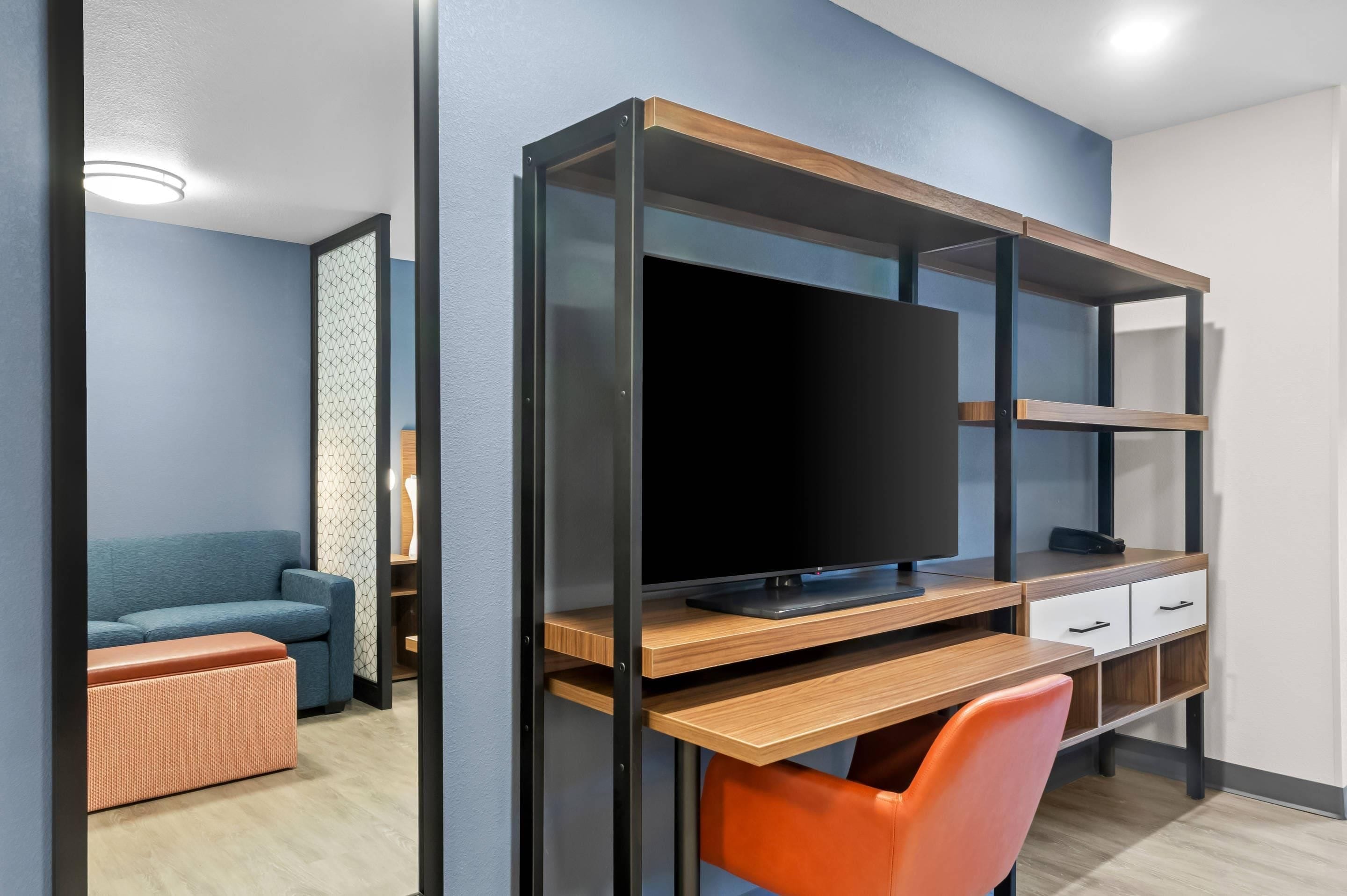 A modern room with a wooden desk, a television, and a blue sofa.