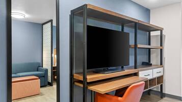 Une chambre moderne avec un bureau en bois, une télévision et un canapé bleu.