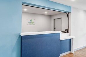 En receptionsdisk med skilt for WoodSpring Suites, et hotel for længere ophold.