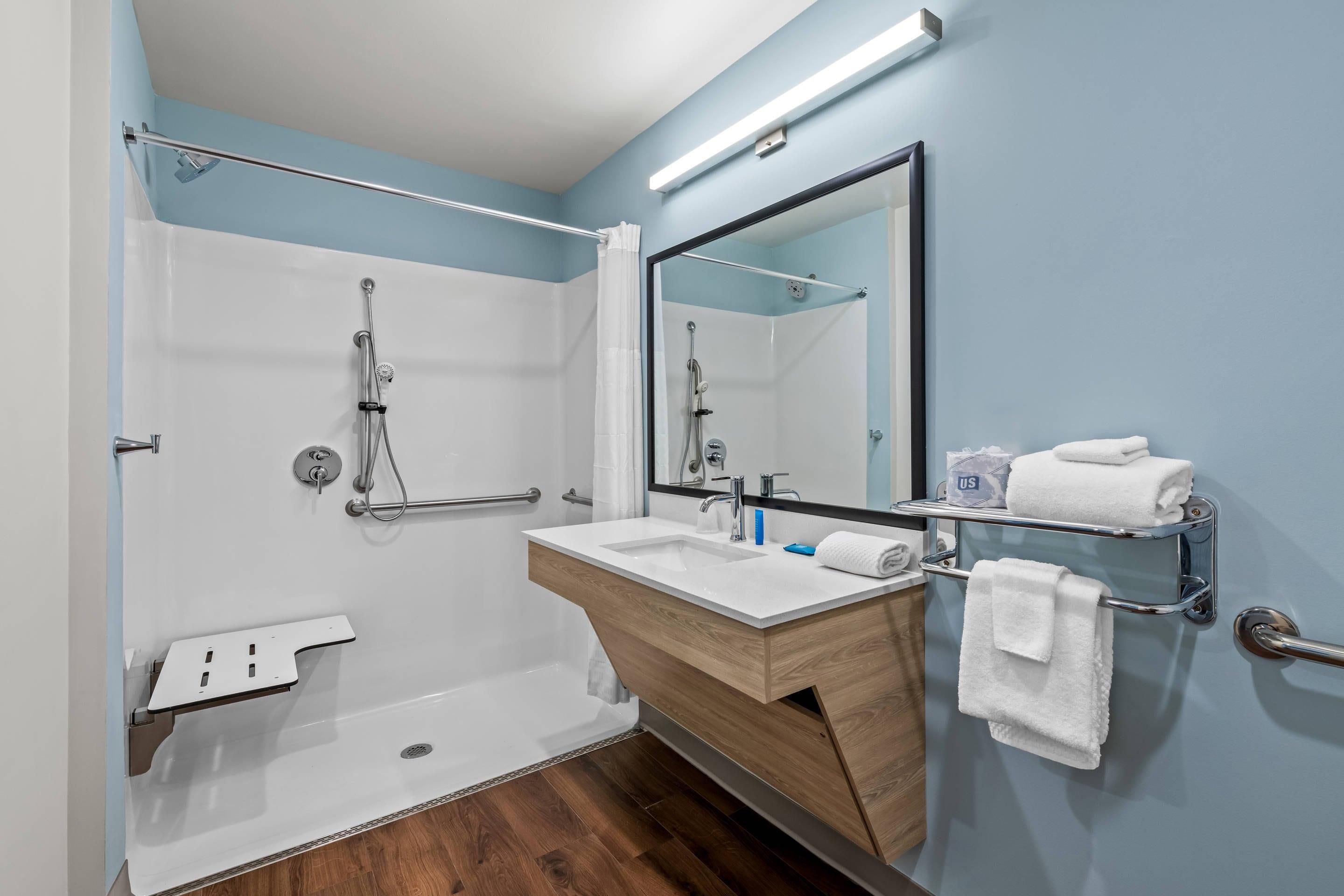 A modern bathroom with a shower, a sink, and a mirror.