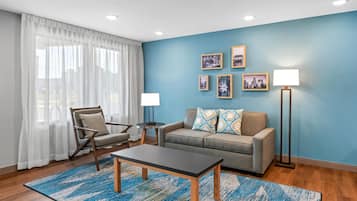 A modern living room with a blue accent wall, a sofa, a chair, a coffee table, and a floor lamp.