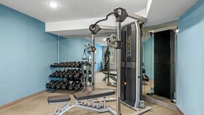 Un gimnasio con una prensa de banca, mancuernas y un espejo.