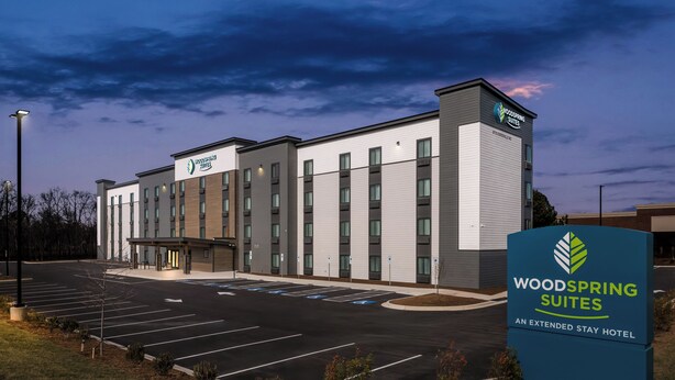 Un hotel moderno con techo plano, varios accesos y aparcamiento.