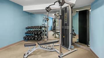 Un gimnasio en casa con una prensa de banca, mancuernas y una jaula para sentadillas.