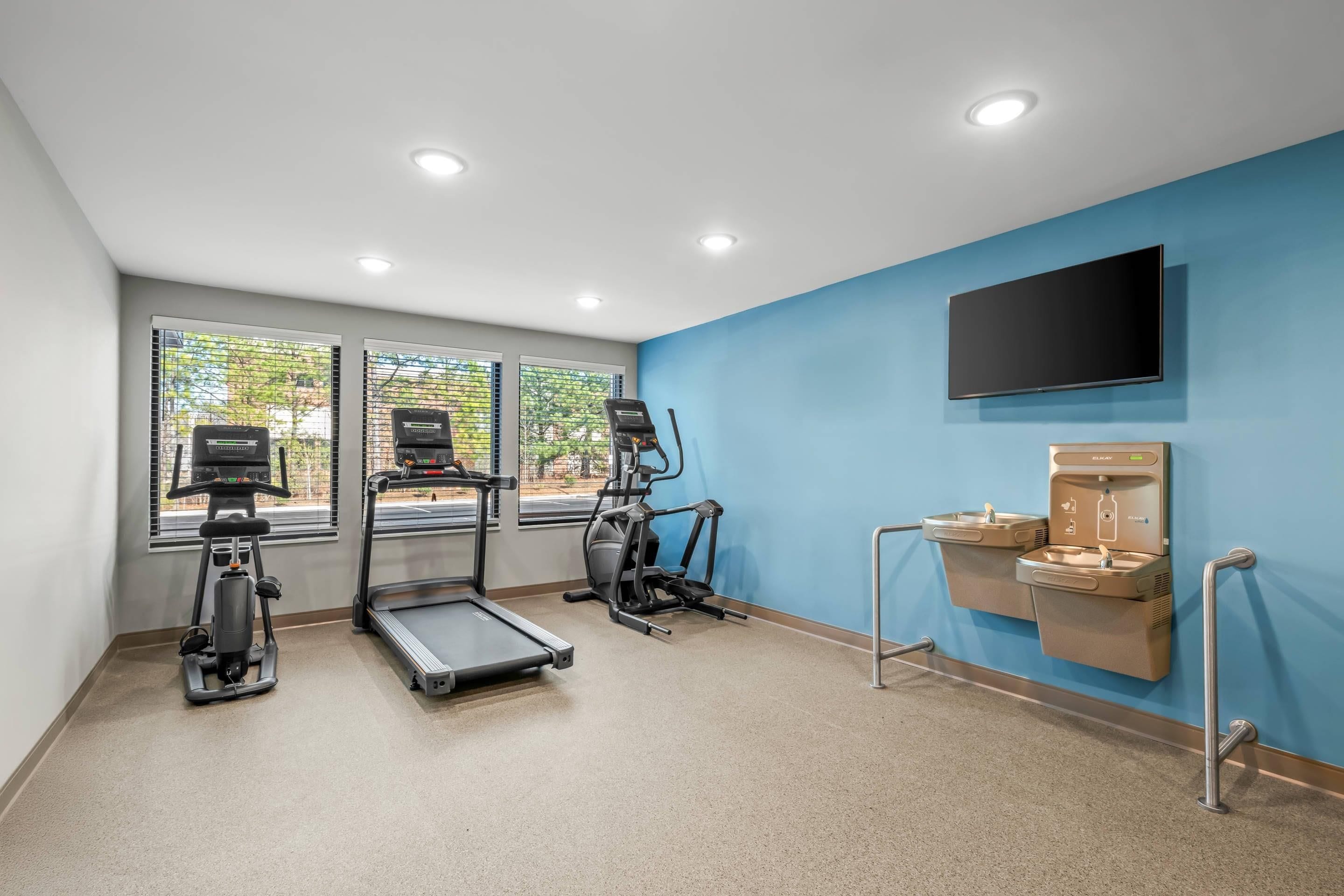 Une salle de remise en forme équipée de tapis de course, de vélos elliptiques et d’un point d’eau.