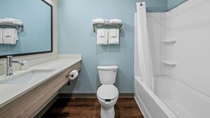 Un baño moderno con tocador de madera, inodoro, ducha y perchero para toallas.