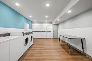A laundry room with a washing machine, dryer, and cabinets. - WoodSpring Suites Charlotte Northlake (Charlotte)