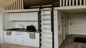 A compact kitchen with a built-in bench, a coffee machine, and a door leading to another room. - Charming Tiny House Getaway With Terrace (Balkbrug)