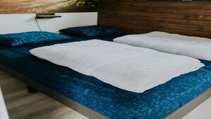 A double bed with blue and white bedding, a wooden headboard, and a framed picture on the wall. - Charming Tiny House Getaway With Terrace (Balkbrug)