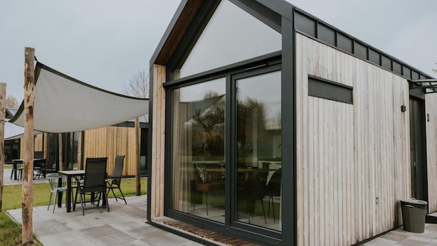 A modern building with large glass windows and a wooden exterior. - Charming Tiny House Getaway With Terrace (Balkbrug)