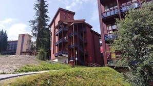 A multi-story building with balconies, a staircase, and a pathway leading to the entrance. - Duplex for 5 People Close to the Slopes and Shops - Quiet Residence in the Village of Charmettoger in Arc 1800 (Bourg-Saint-Maurice)